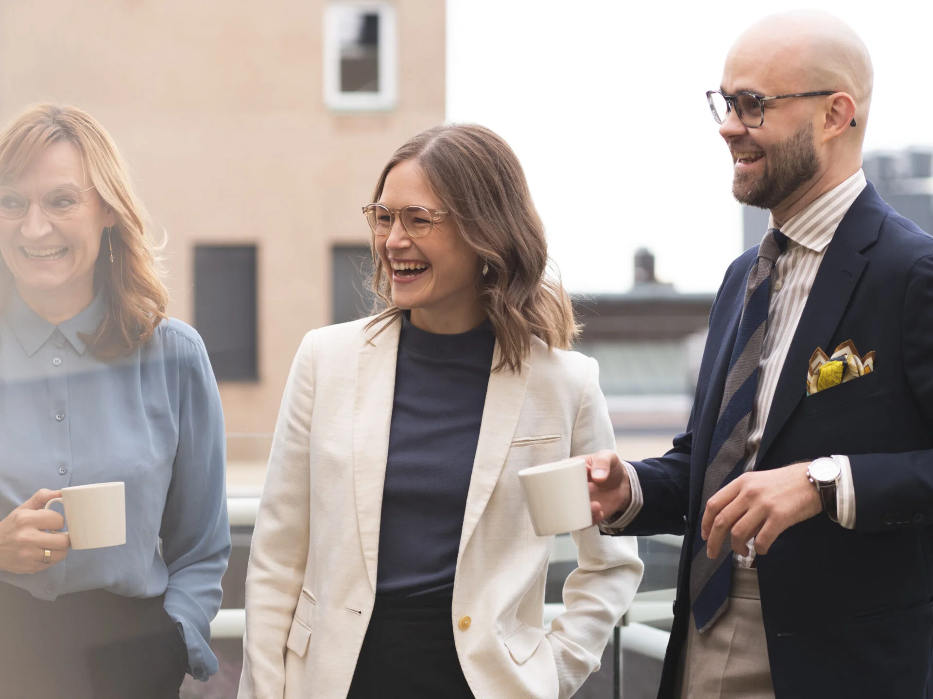 Three people smiling while holding coffee cups