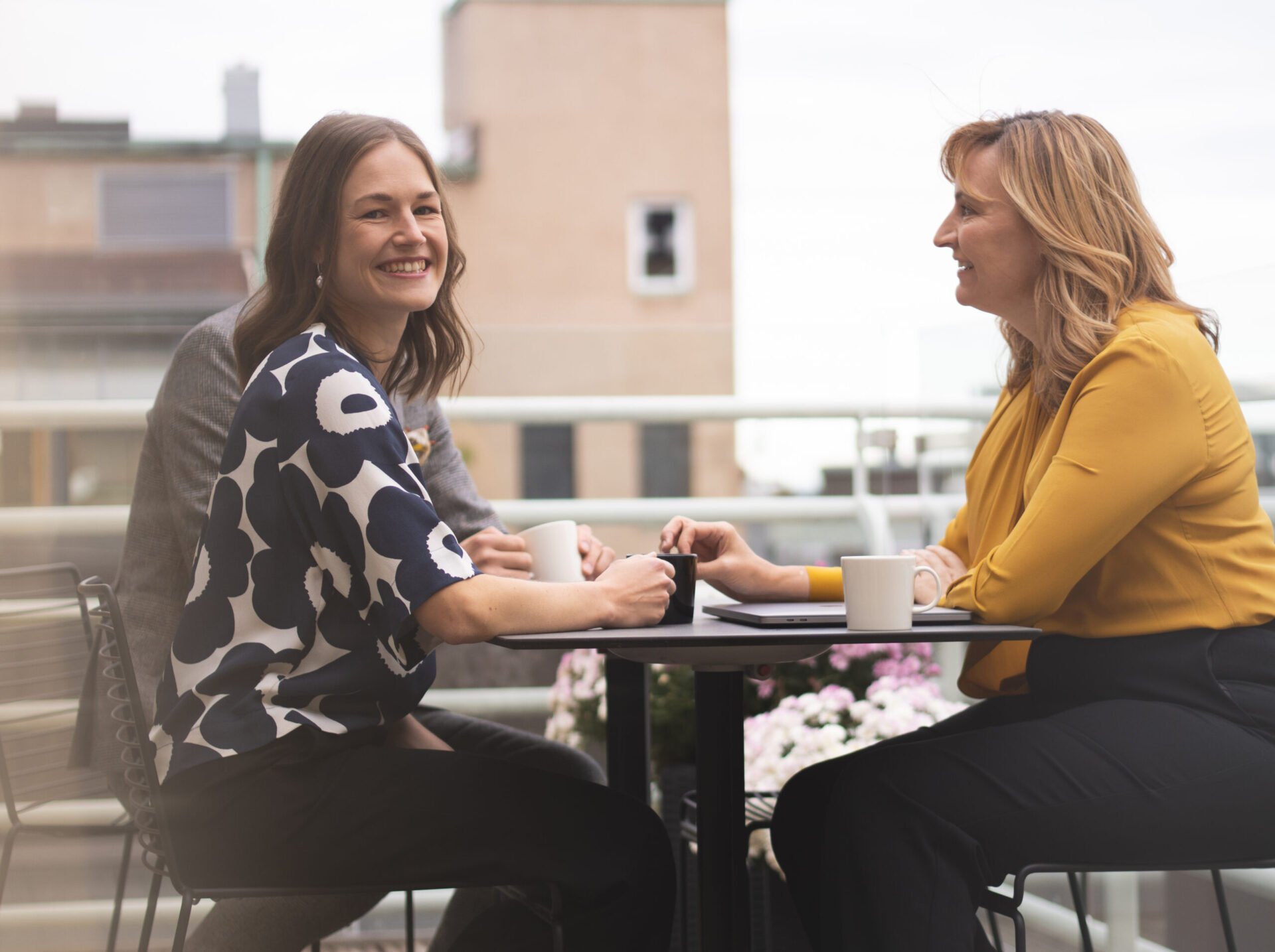 Woman having a coffee break with colleagues on a balcony in a law firm