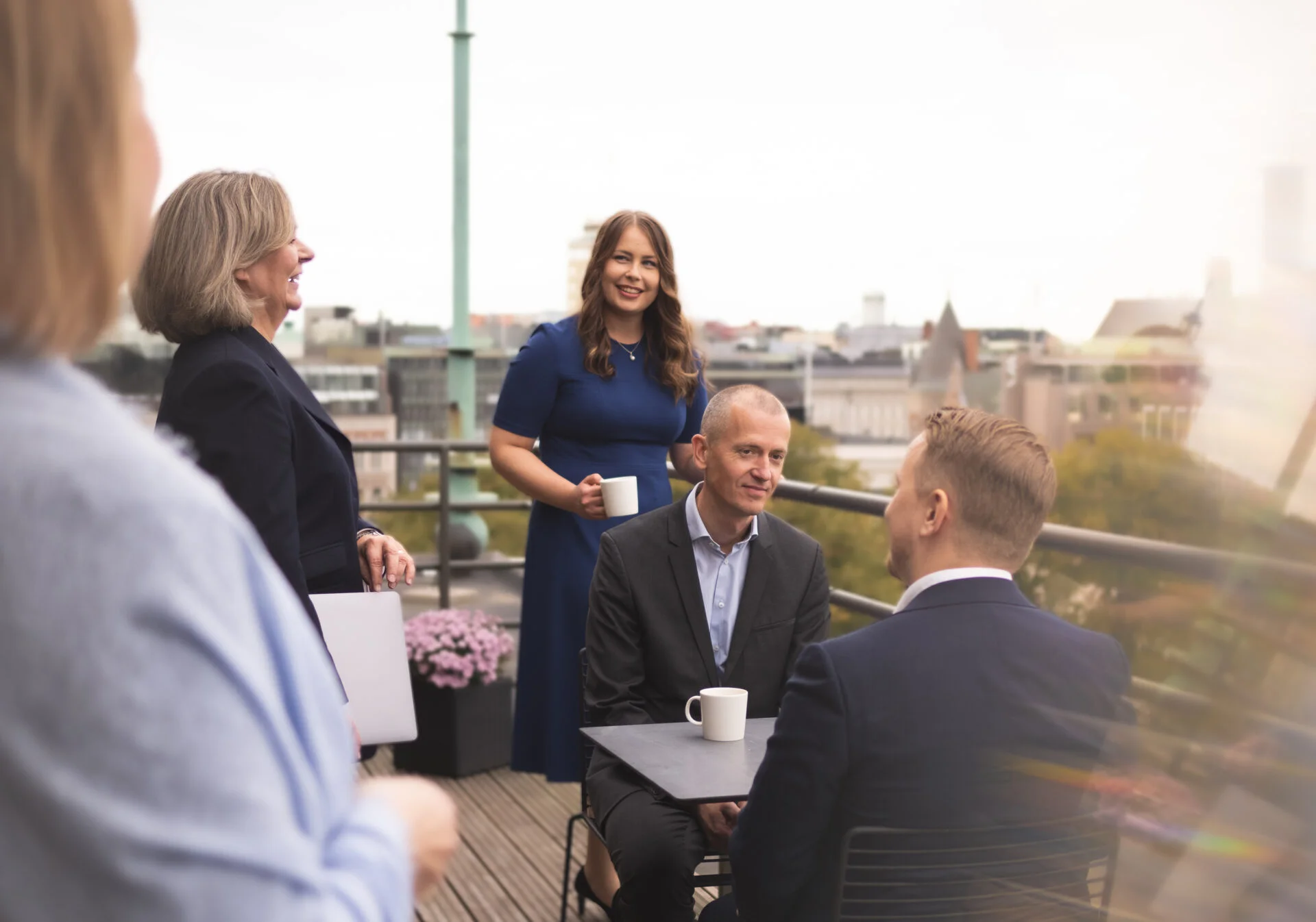 People smiling and having a meeting on a balcony with a view of Helsinki