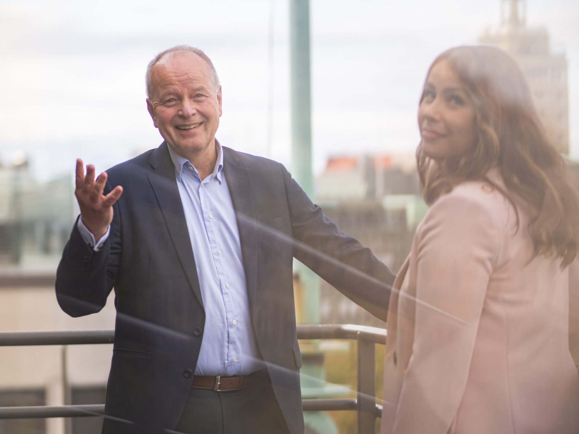 Man smiling and waving hand on the balcony of a law firm