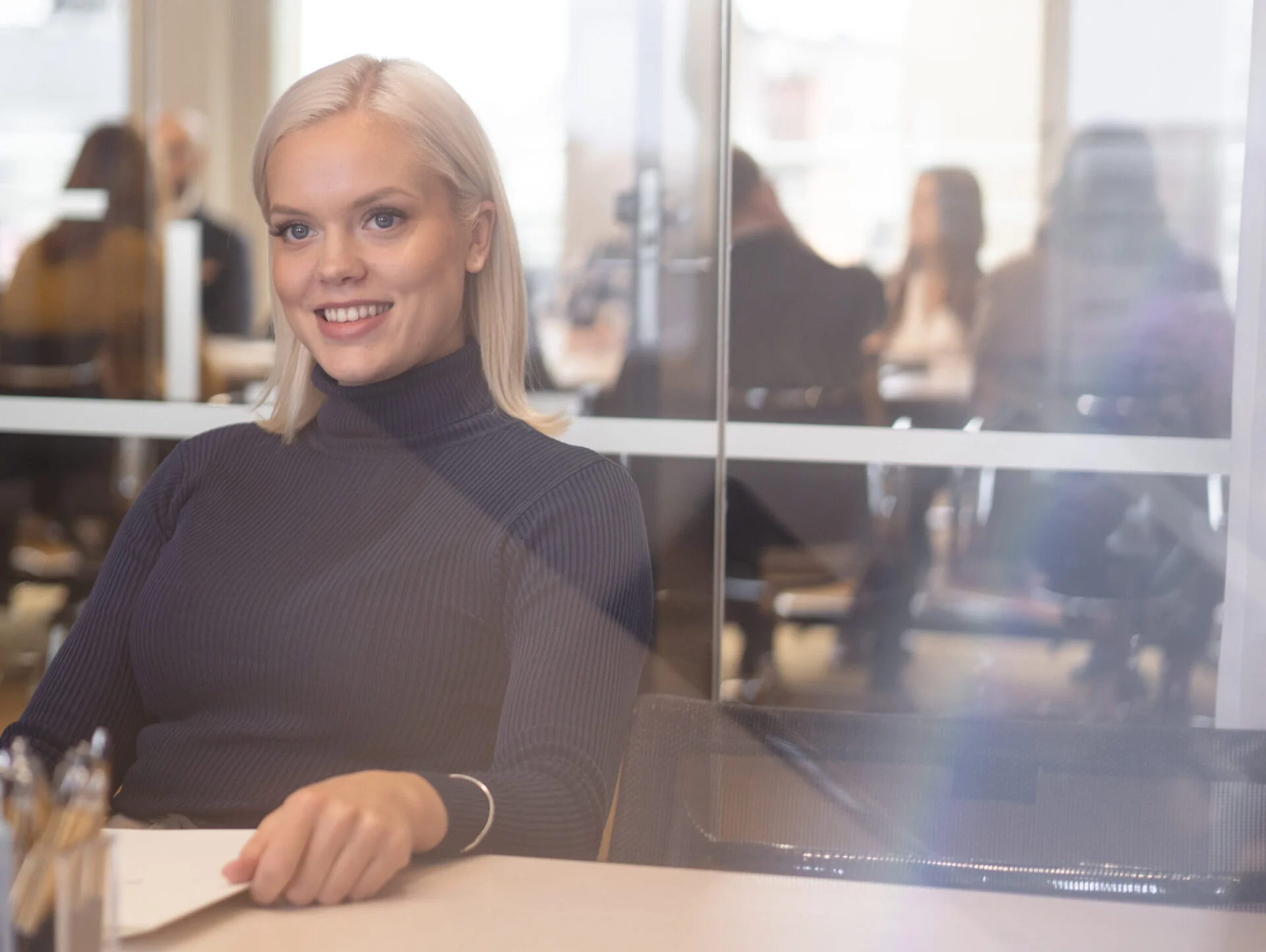 Smiling woman in a law firm meeting room with people in the background