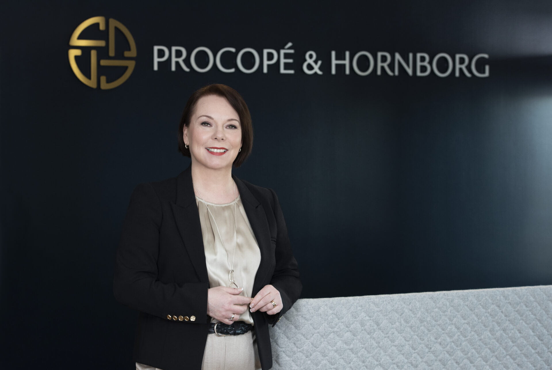 CEO smiling in front of a law firm logo in the lobby